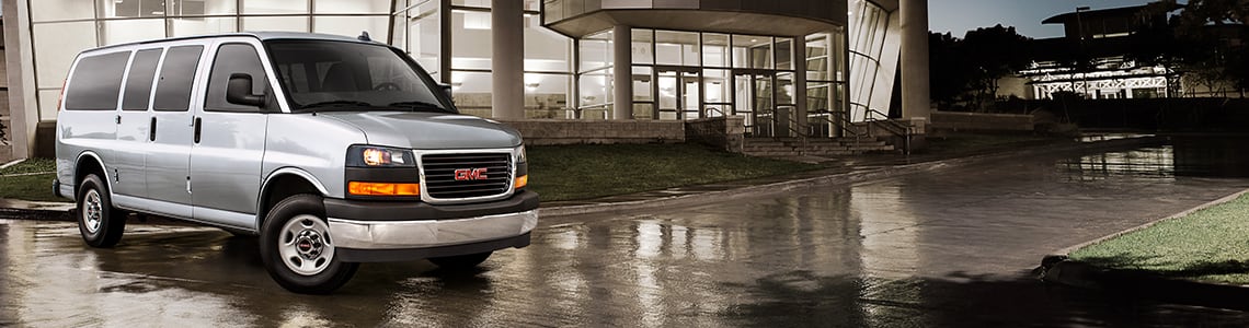 2024 GMC Savana Passenger Van side profile in a wet driveway
